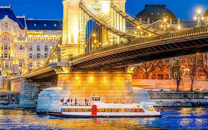 Budapest Danube River nighttime cruise with illuminated cityscape and historic buildings.