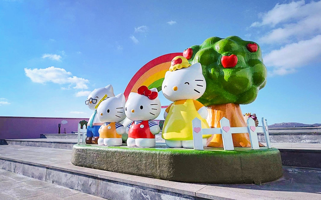 Hello Kitty statues with rainbow and apple tree at Hello Kitty Island.