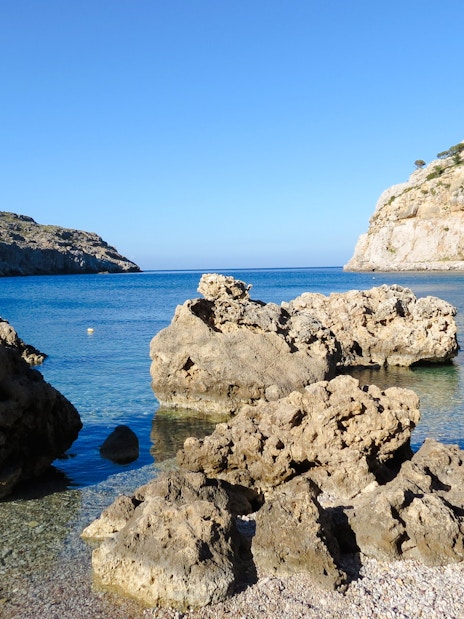 Rocky shoreline of Navarone Bay with clear blue water, Island of Rhodes, Greece.