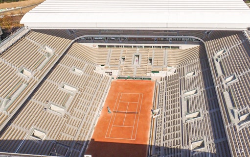 Roland Garros Stadium interior with clay tennis court and surrounding seating area.