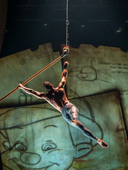 Performer suspended in air during "Drawn to Life" show with animated backdrop.