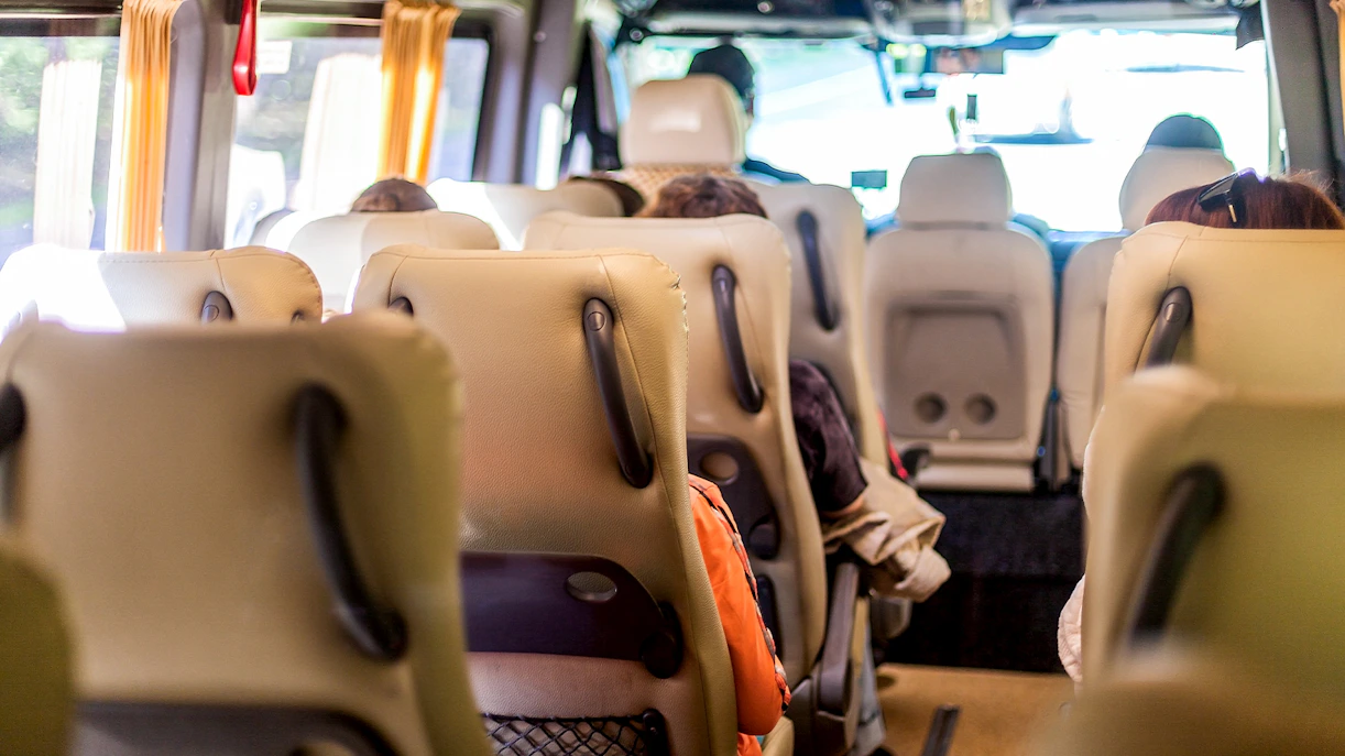 Minivan interior with beige seats and passengers seated, view towards the front.