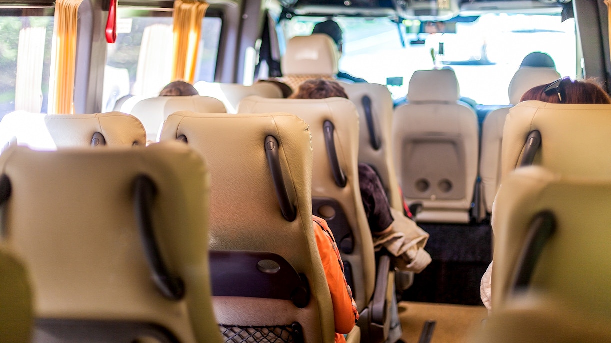 Minivan interior with beige seats and passengers seated, view towards the front.
