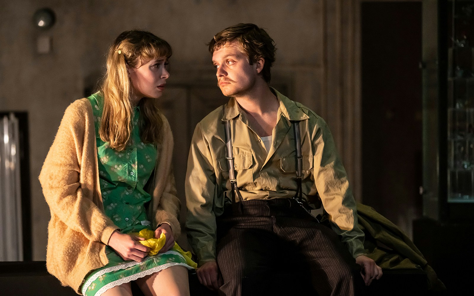 Two actors in a scene from "The Glass Menagerie" play, sitting closely and engaging in conversation.