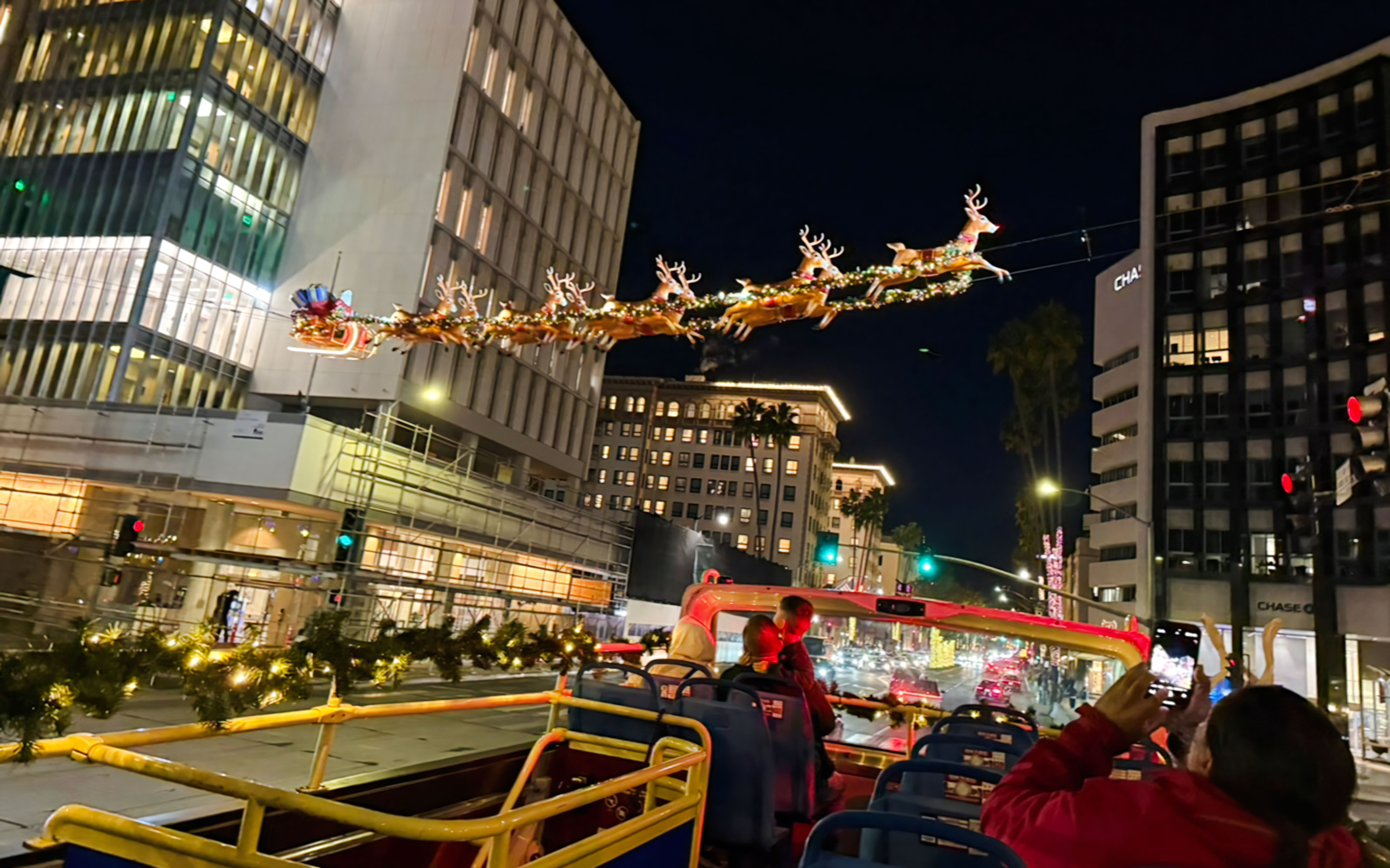 Tourists on Los Angeles HOHO bus viewing holiday lights and Santa sleigh display.