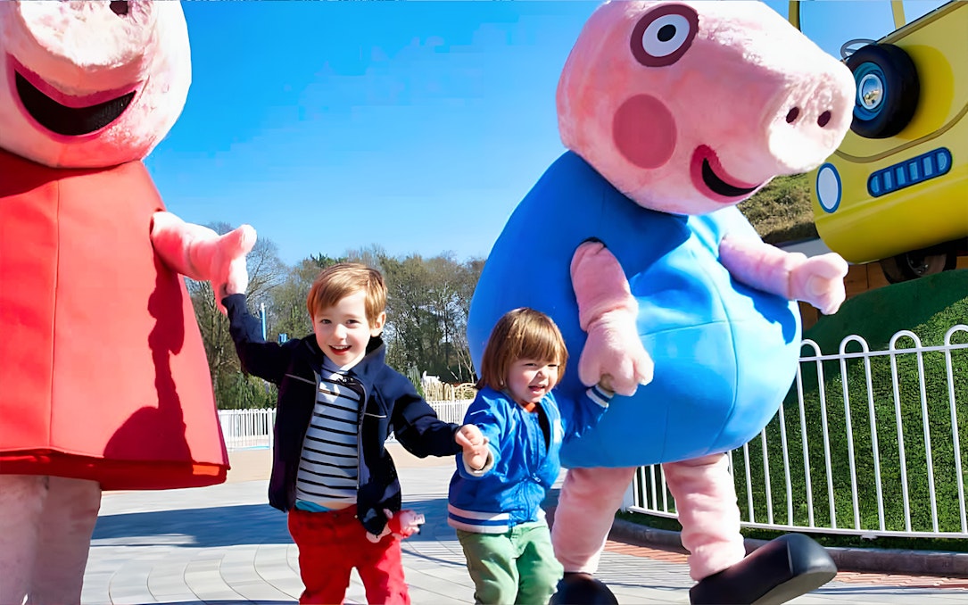 Children holding hands with Peppa Pig characters at Paultons Park, UK.