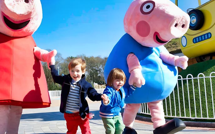 Children holding hands with Peppa Pig characters at Paultons Park, UK.