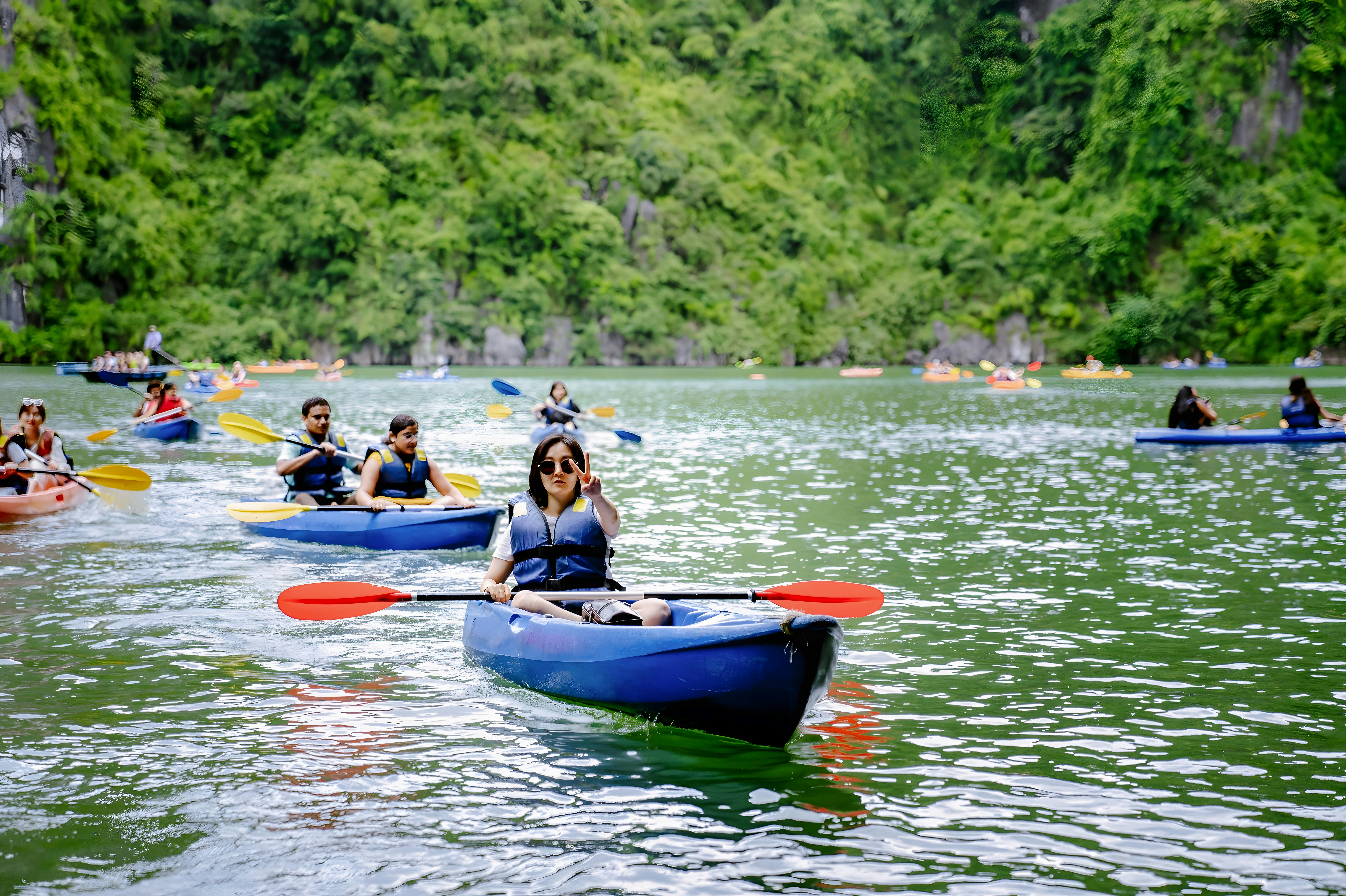 Travellers kayaking among limestone karsts in Ha Long Bay, Vietnam.