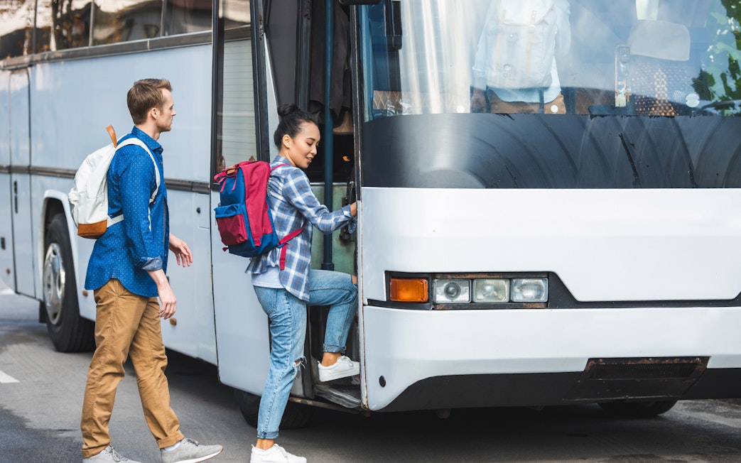 Tourists boarding air-conditioned coach bus for transfer to Montserrat Monastery.