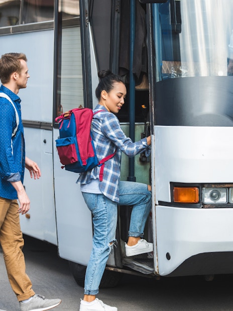 Tourists boarding air-conditioned coach bus for transfer to Montserrat Monastery.