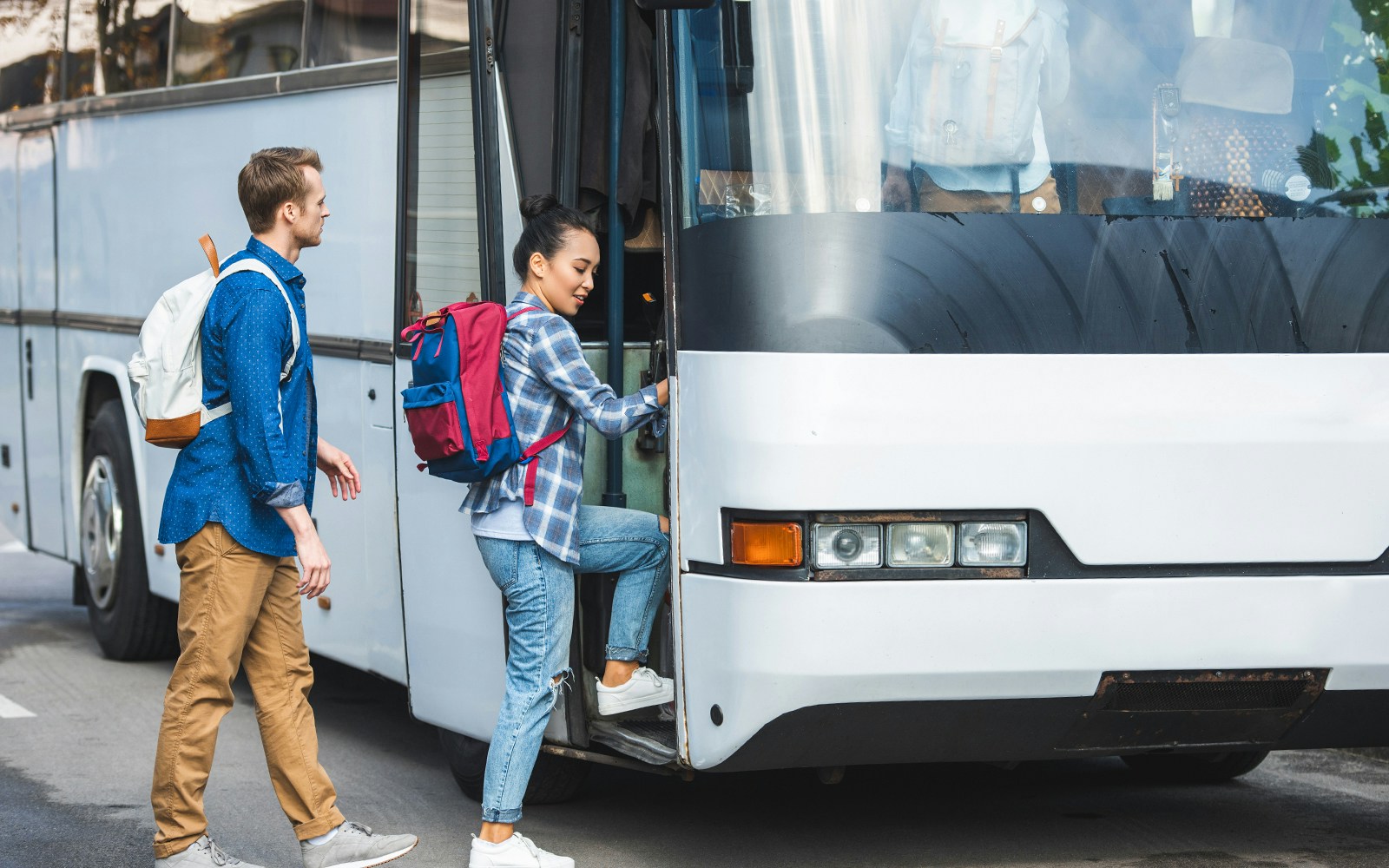 Tourists boarding air-conditioned coach bus for transfer to Montserrat Monastery.