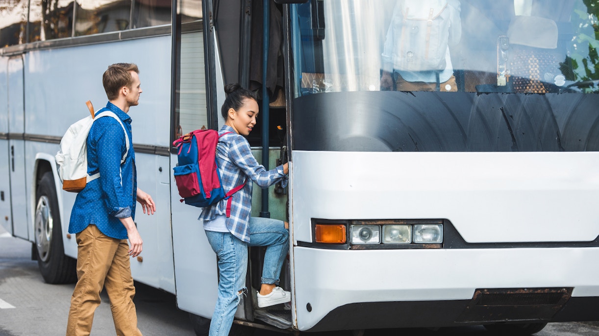 Tourists boarding air-conditioned coach bus for transfer to Montserrat Monastery.