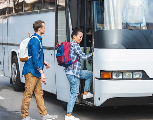 Tourist boarding air-conditioned coach bus for transfer to Montserrat Monastery.