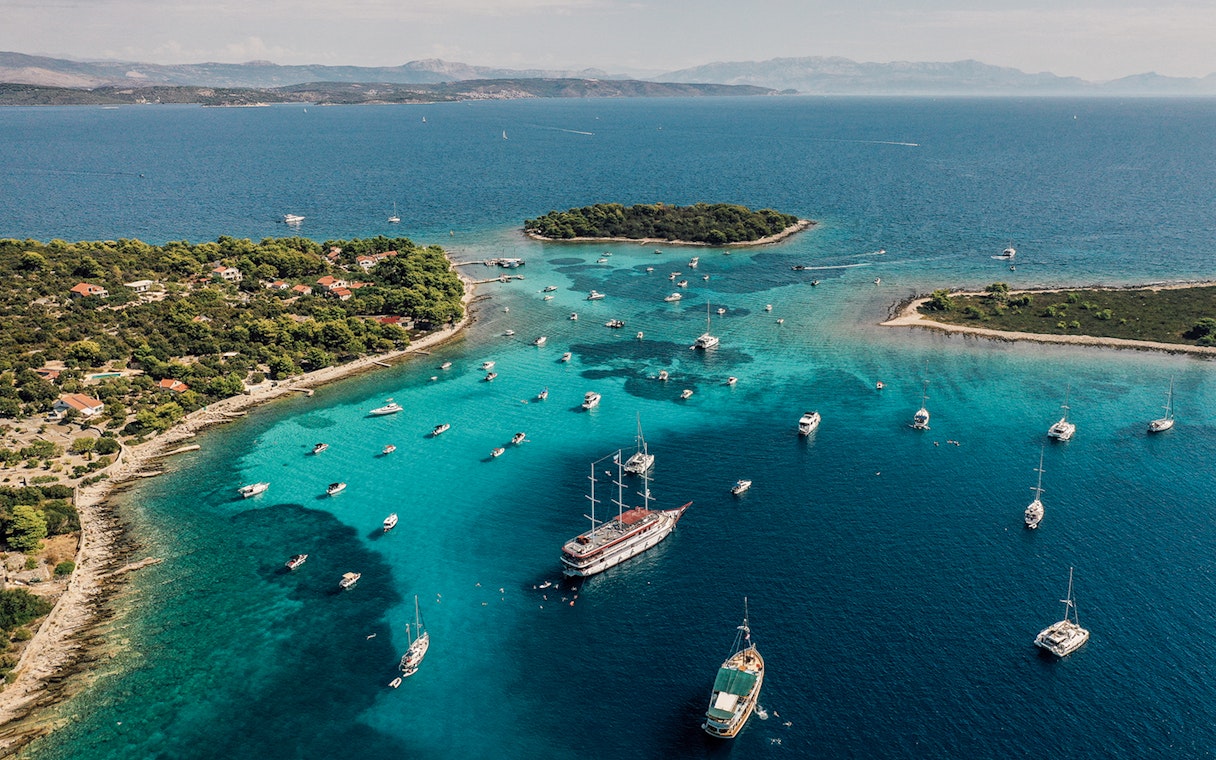 Aerial view of boats in the Blue Lagoon, Croatia, surrounded by turquoise waters and lush islands.