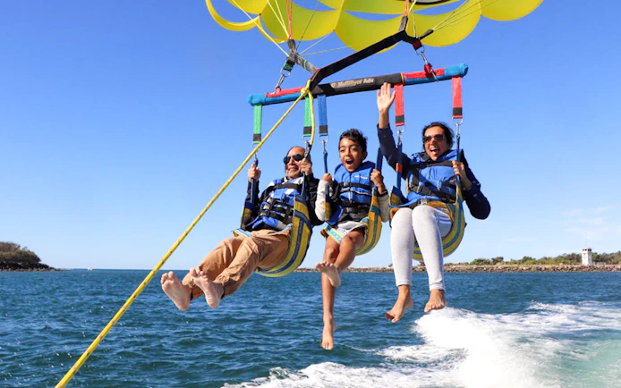 Parasailing over ocean with three people enjoying the Jet Ski & Parasail Experience.