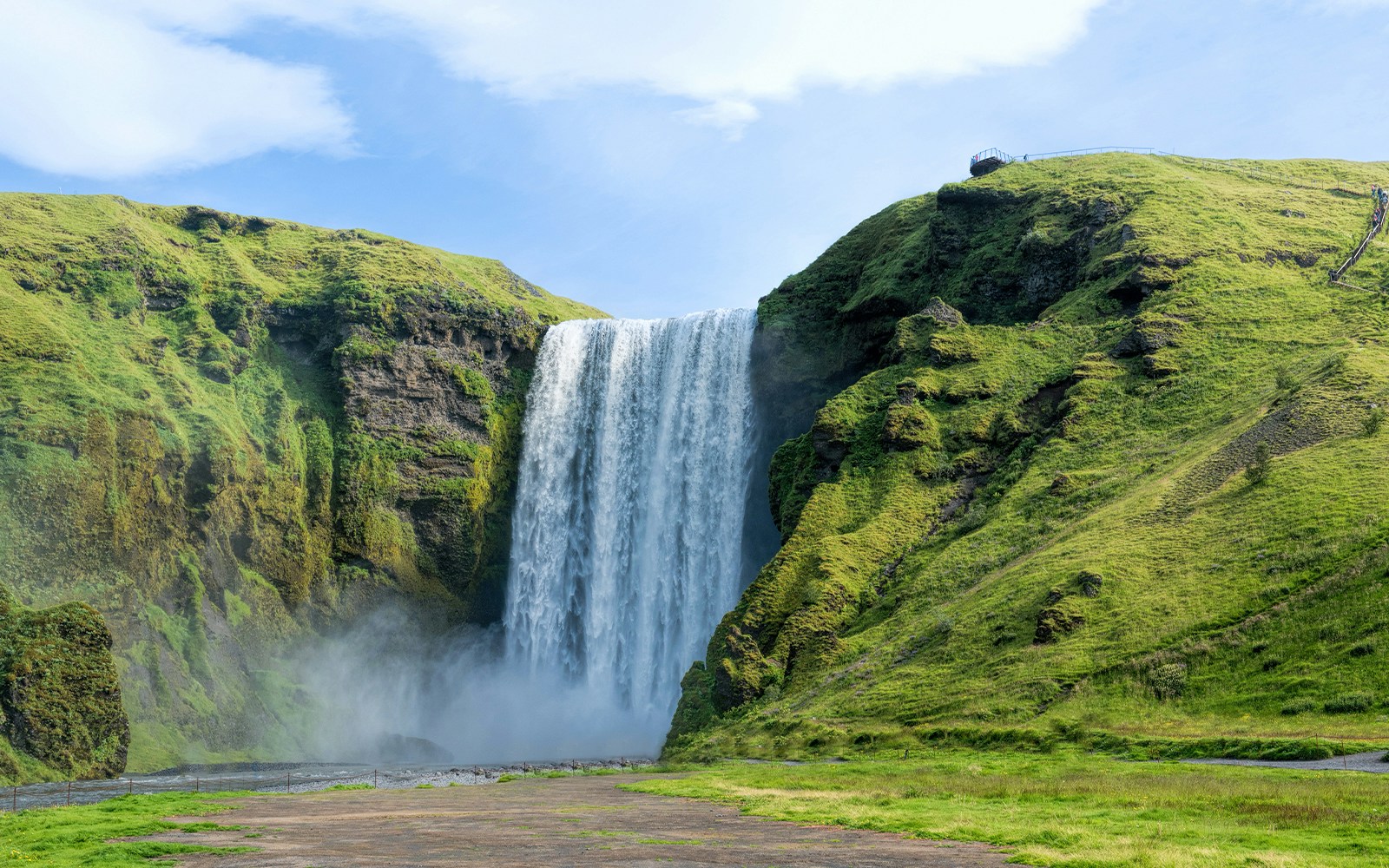 Skógafoss waterfall cascading over green cliffs in Iceland.
