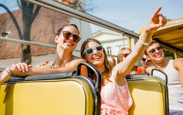 Tourists enjoying a Darwin bus tour, smiling and pointing at sights.