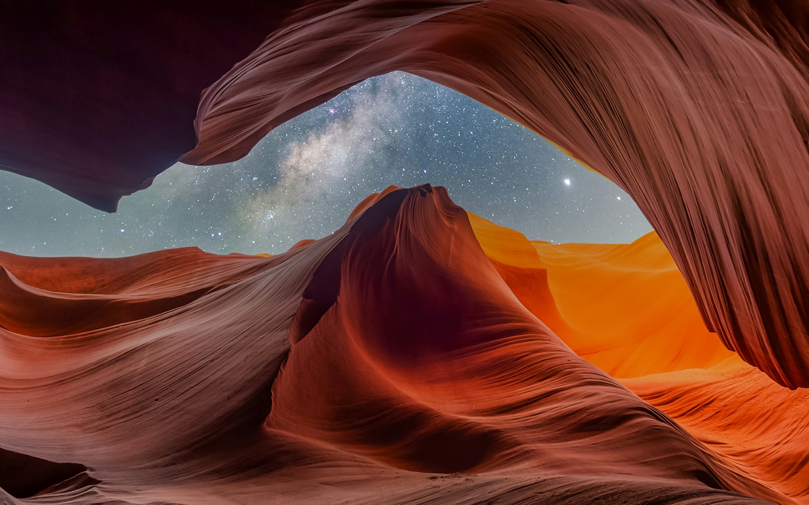 Antelope Canyon rock formations with Milky Way visible in the night sky.