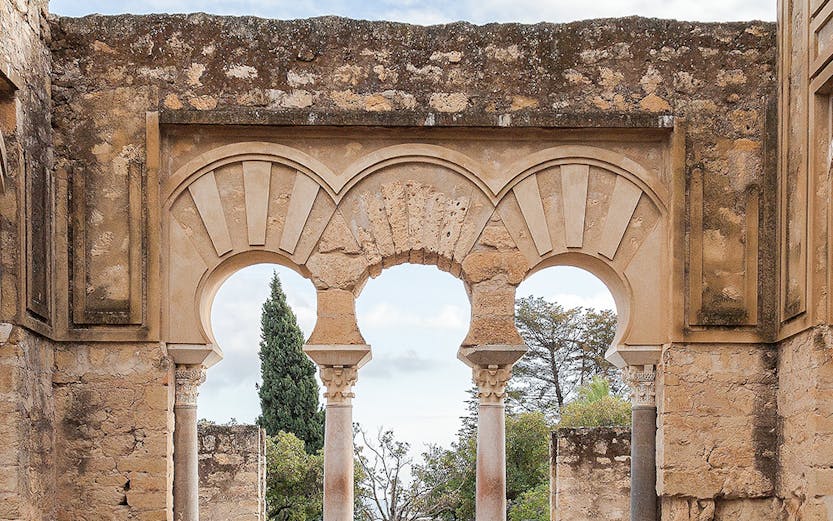 Medina Azahara arches in Cordoba, Spain, with stone walls and garden view.