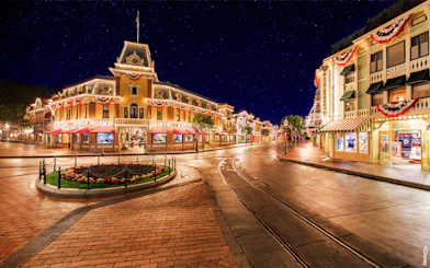 Main Street USA at night, Disneyland Park California, with illuminated shops and decorations.