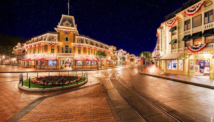 Main Street USA at night, Disneyland Park California, with illuminated shops and decorations.
