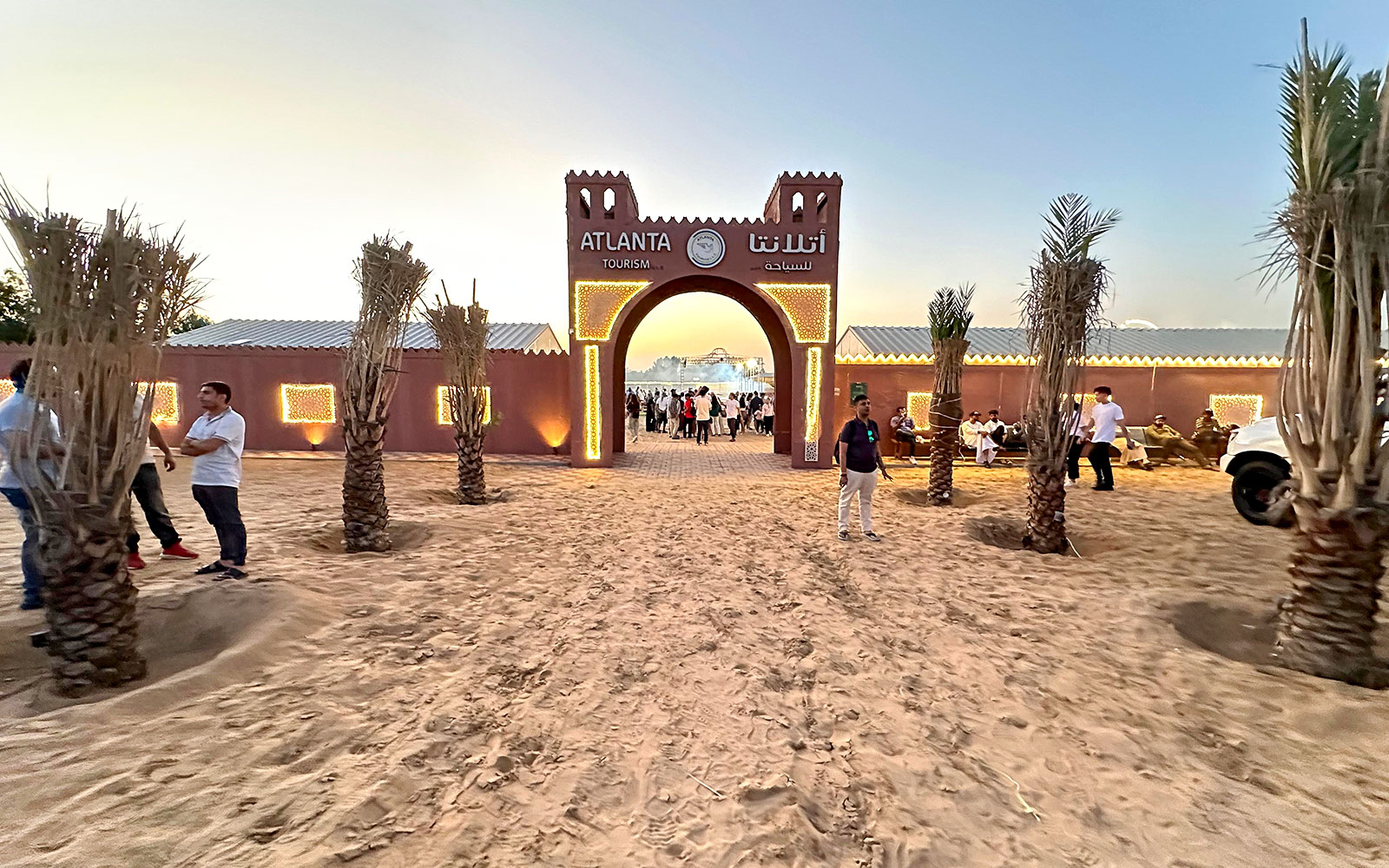 Desert safari entrance with people gathering at sunset, Dubai.