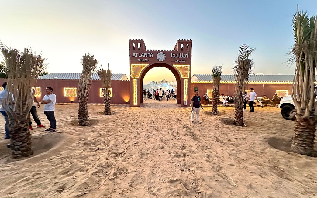 Desert safari entrance with people gathering at sunset, Dubai.