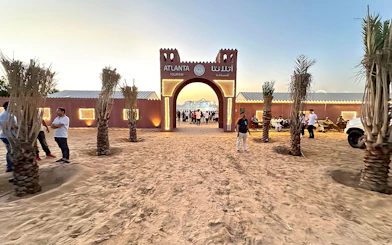 Desert safari entrance with people gathering at sunset, Dubai.