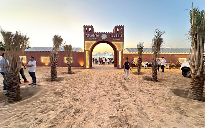 Desert safari entrance with people gathering at sunset, Dubai.