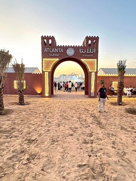 Desert safari entrance with people gathering at sunset, Dubai.