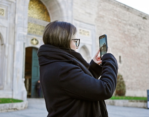 Adult woman taking photo of Topkapi Palace courtyard in Istanbul, Turkey.