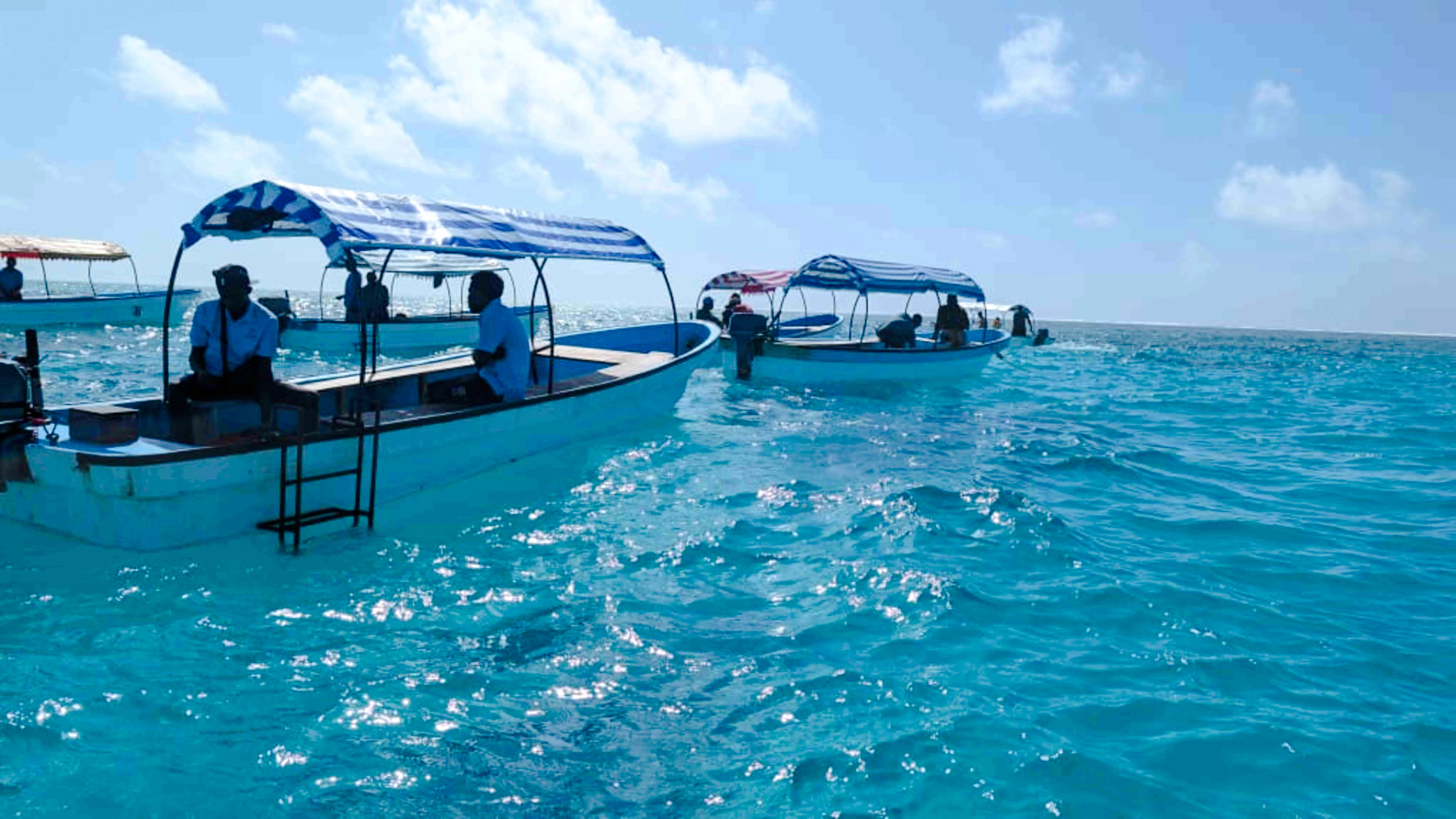 Boats on clear blue water during Mnemba snorkeling tour, Zanzibar.