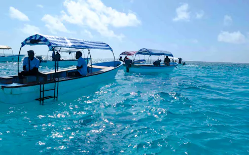 Boats on clear blue water during Mnemba snorkeling tour, Zanzibar.