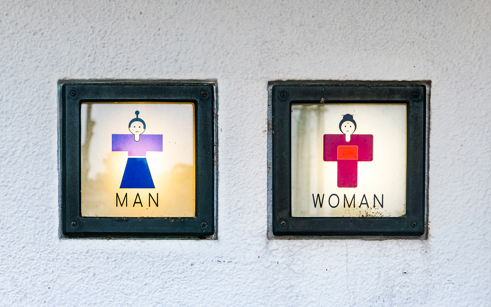 Public restroom signs in Japan with traditional clothing icons for men and women.