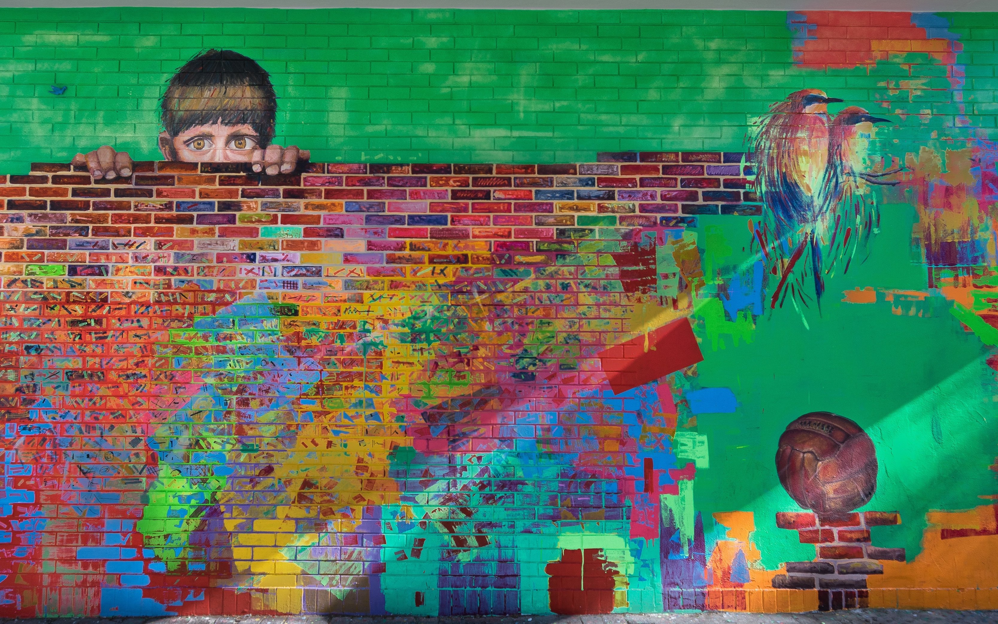 Colorful graffiti mural with a child peeking over a brick wall in Buenos Aires.