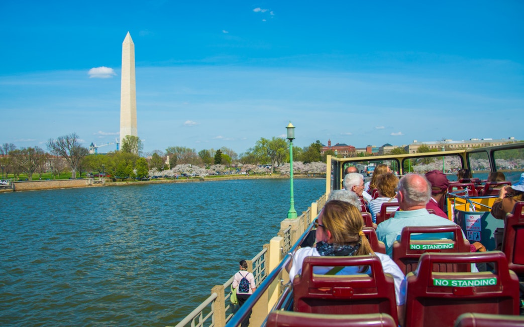 Tourists on open-top bus viewing Washington Monument, Washington DC.