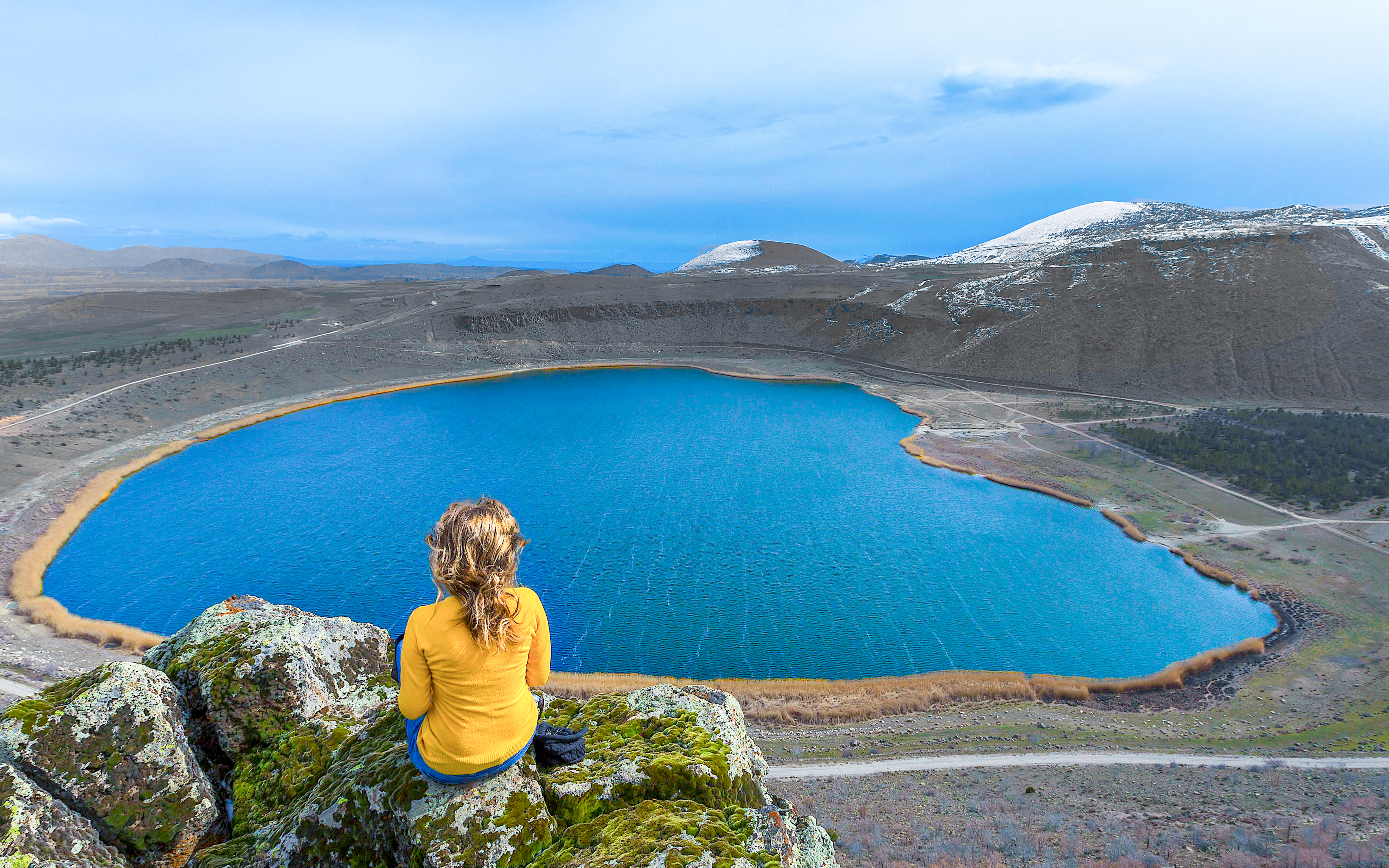 Person sitting on rocks overlooking Narlıgöl crater lake in Niğde, Turkey.