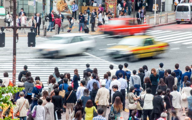 Crowd waiting at a busy Tokyo crosswalk near Narita Airport transfer area.