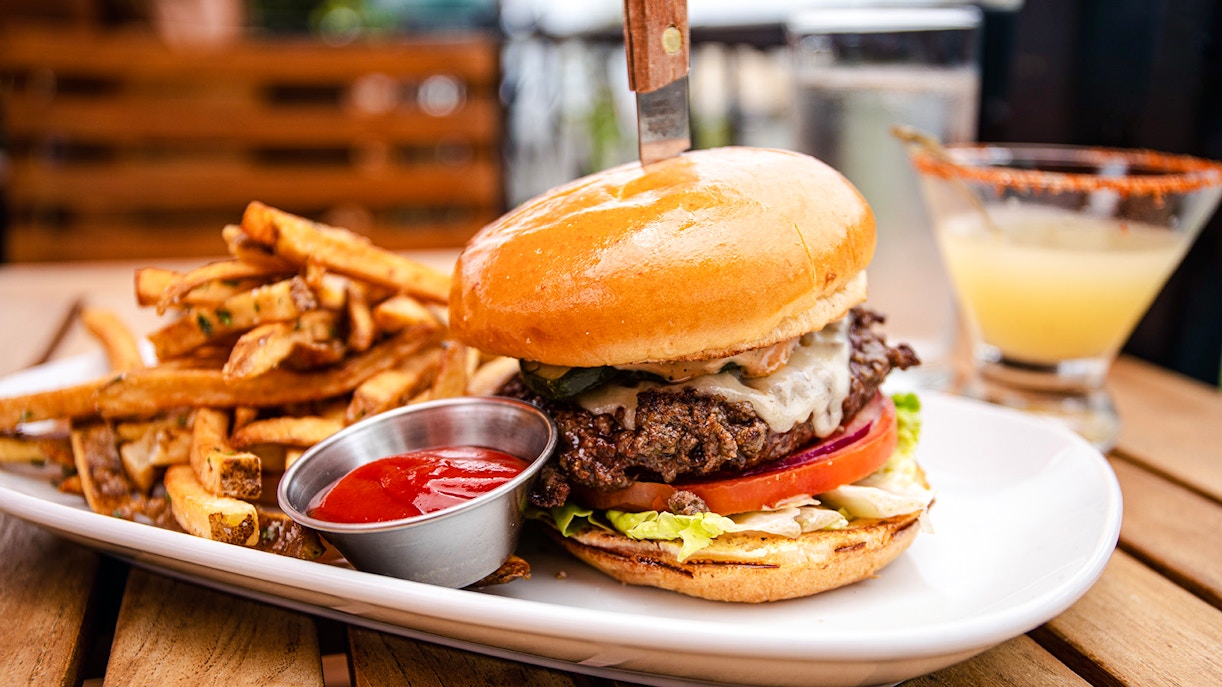 Cheeseburger with fries and ketchup on a plate, served with a drink.