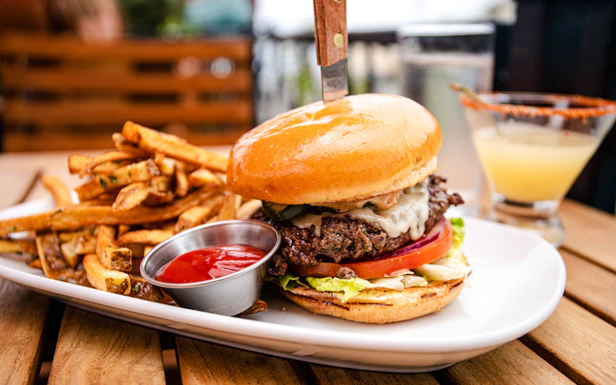 Cheeseburger with fries and ketchup on a plate, served with a drink.