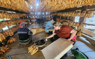 Visitors learning traditional crafts in a corn storage house, Mu Cang Chai motorbike tour.