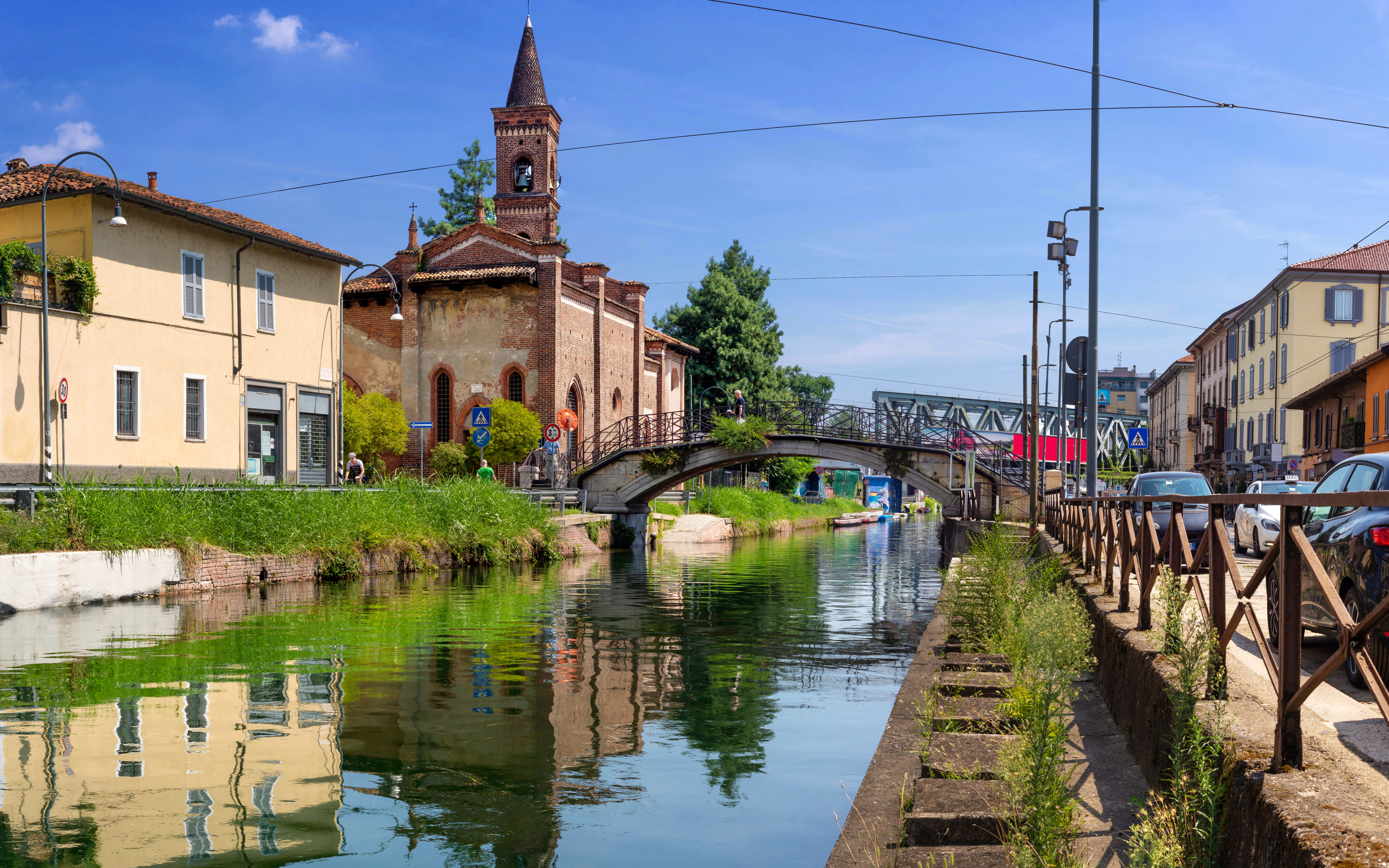 Church of San Cristoforo by a canal in Milan with a stone bridge and surrounding buildings.