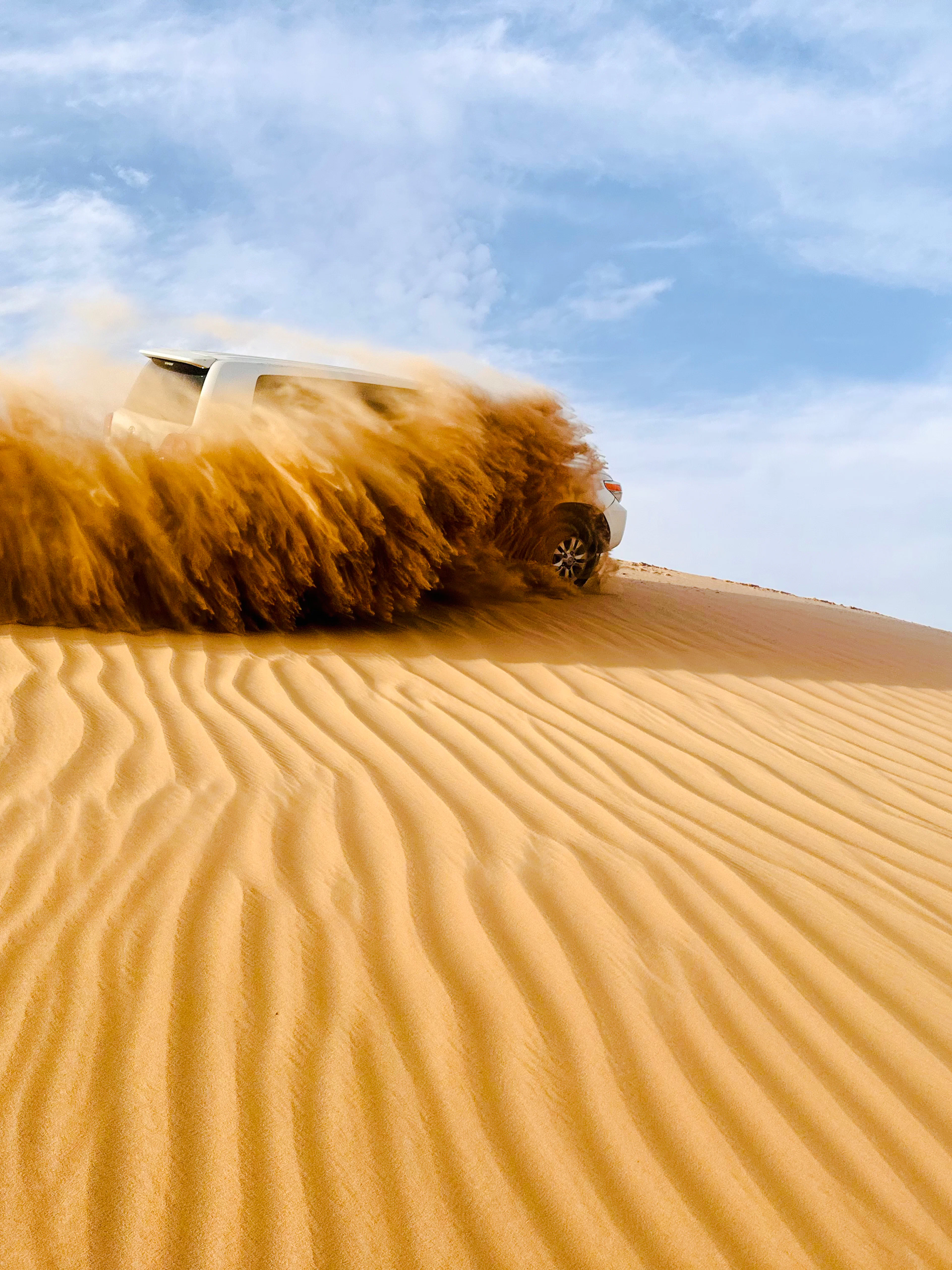 SUV driving through sand dunes during Abu Dhabi morning desert safari.