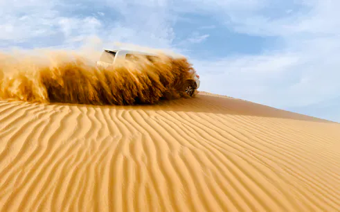 SUV driving through sand dunes during Abu Dhabi morning desert safari.