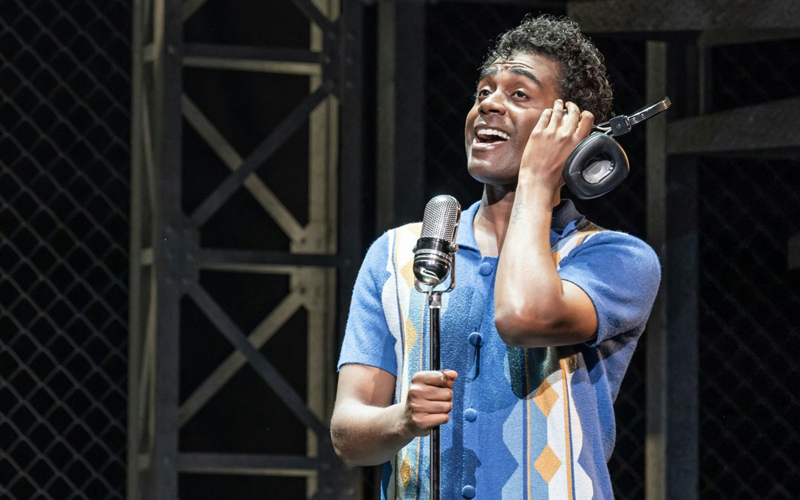 Performer singing into a microphone during a Jersey Boys show.