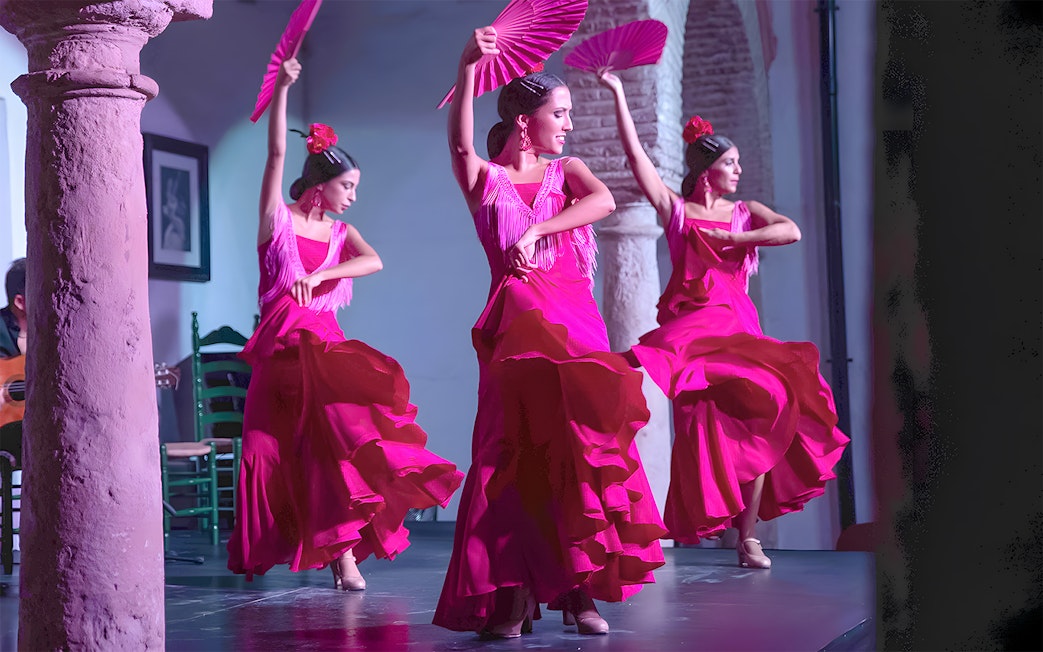Flamenco dancers performing at Tablao Cardenal in vibrant pink dresses.