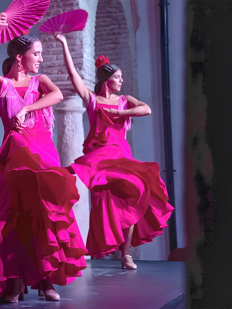 Flamenco dancers performing at Tablao Cardenal in vibrant pink dresses.