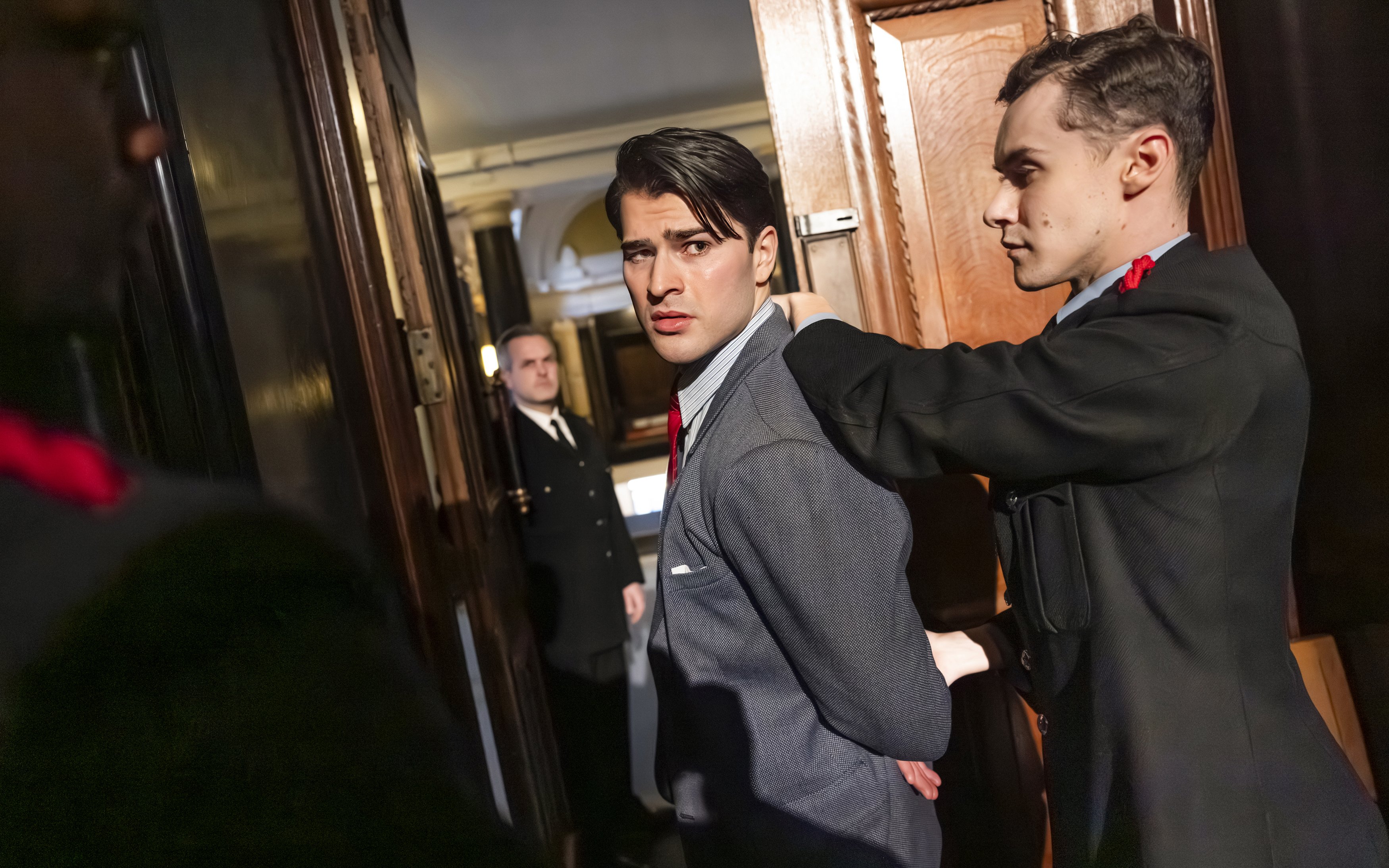 Actor being escorted by guards in a courtroom scene from "Witness for the Prosecution" performance.