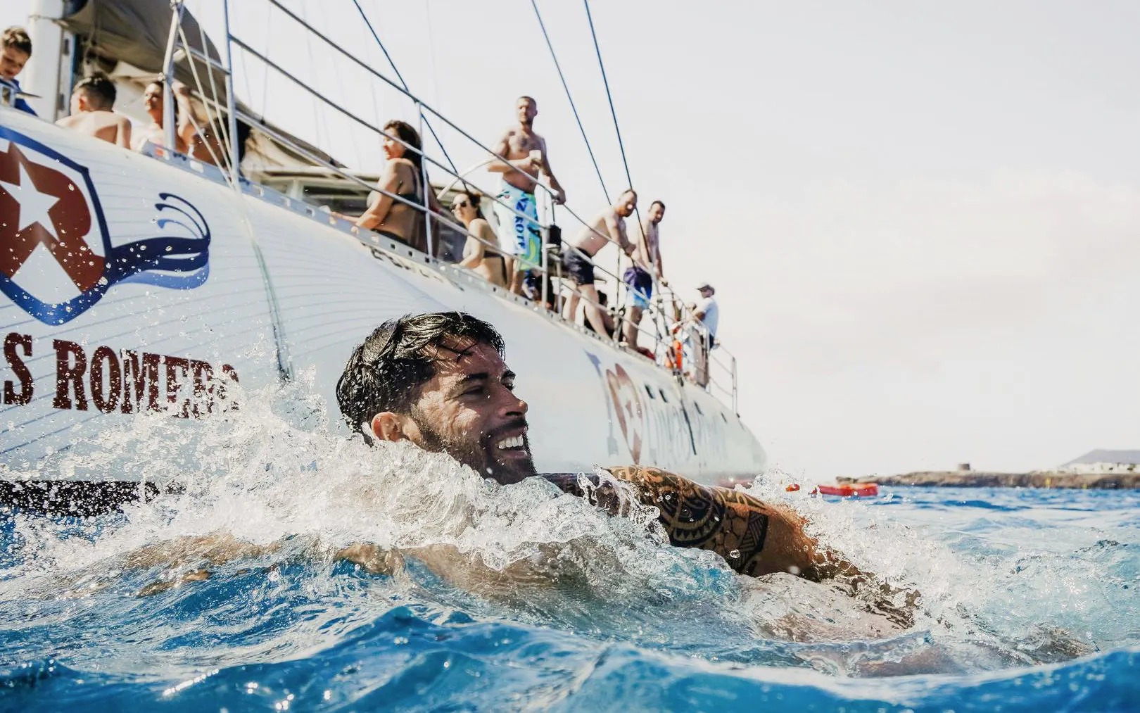 Man swimming near a boat during a mini cruise to Papagayo Beaches, Lanzarote.