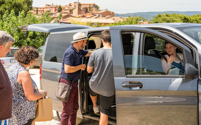 People boarding a minivan with Roussillon landscapes in the background, Provence.